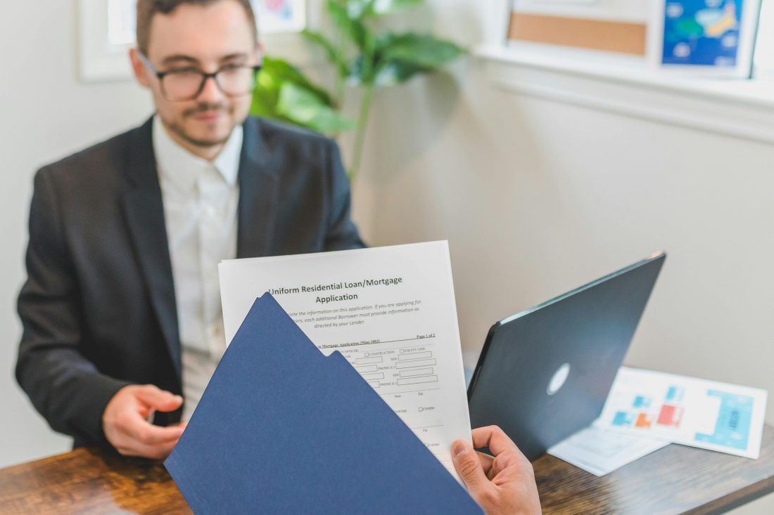 Loan officer reviewing mortgage application with borrower, illustrating borrower verification, income assessment, and lending approval process.