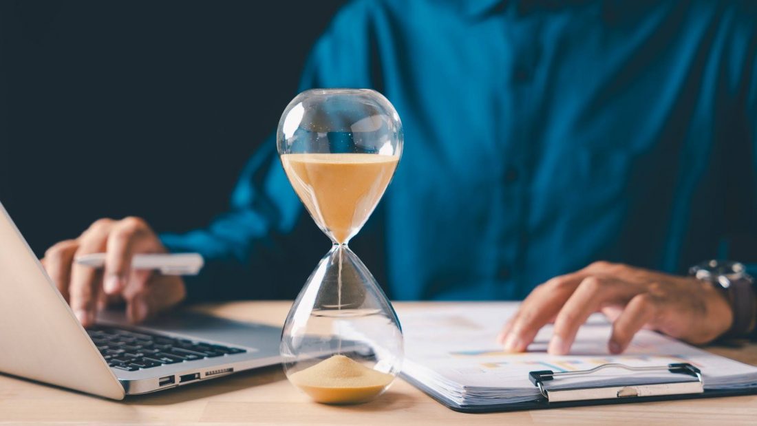 Hourglass on a desk representing background check turnaround times and employer screening process expectations